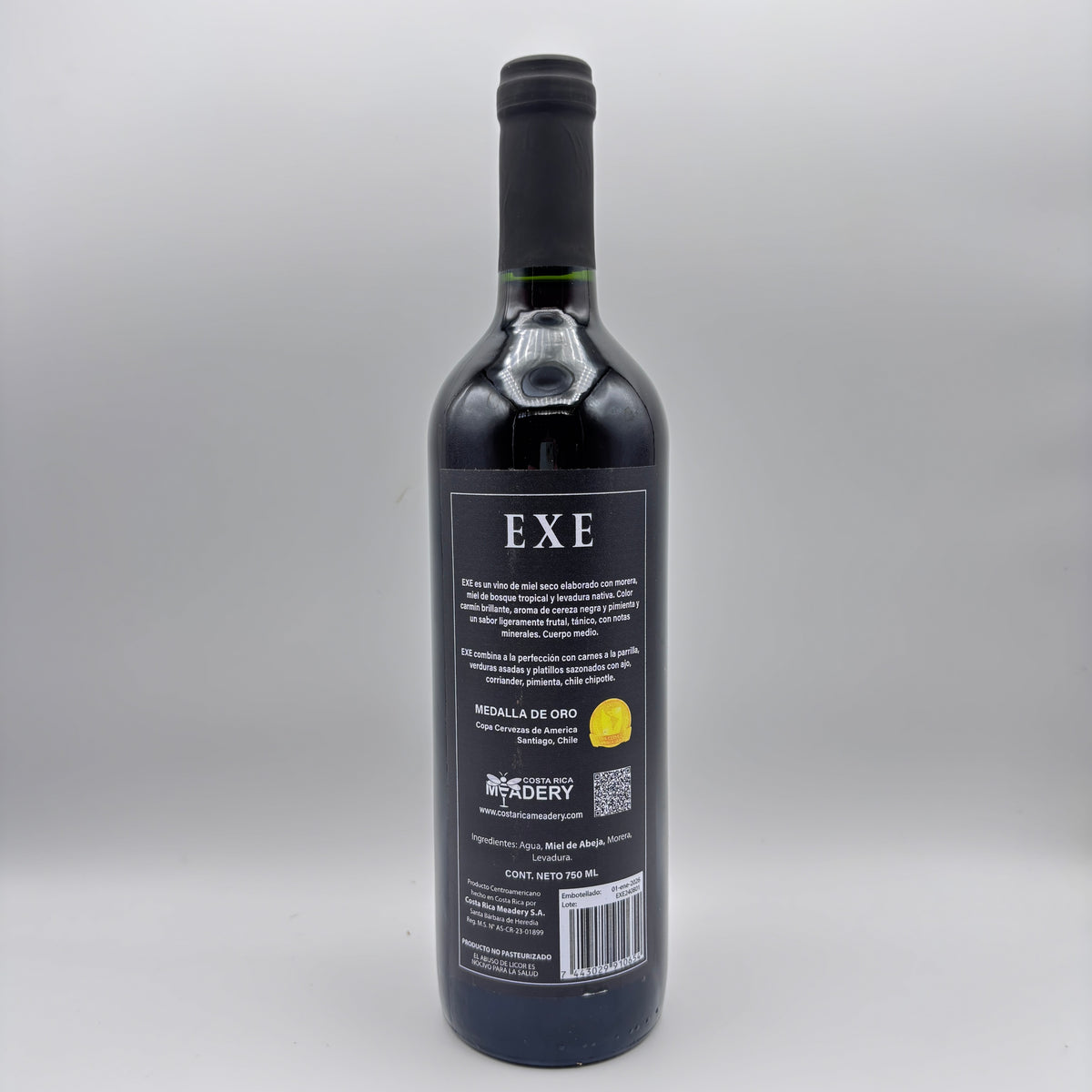 Vista trasera de la botella de hidromiel Exe mostrando la contraetiqueta con detalles del producto, sello de Medalla de Oro y código de barras sobre un fondo neutro.